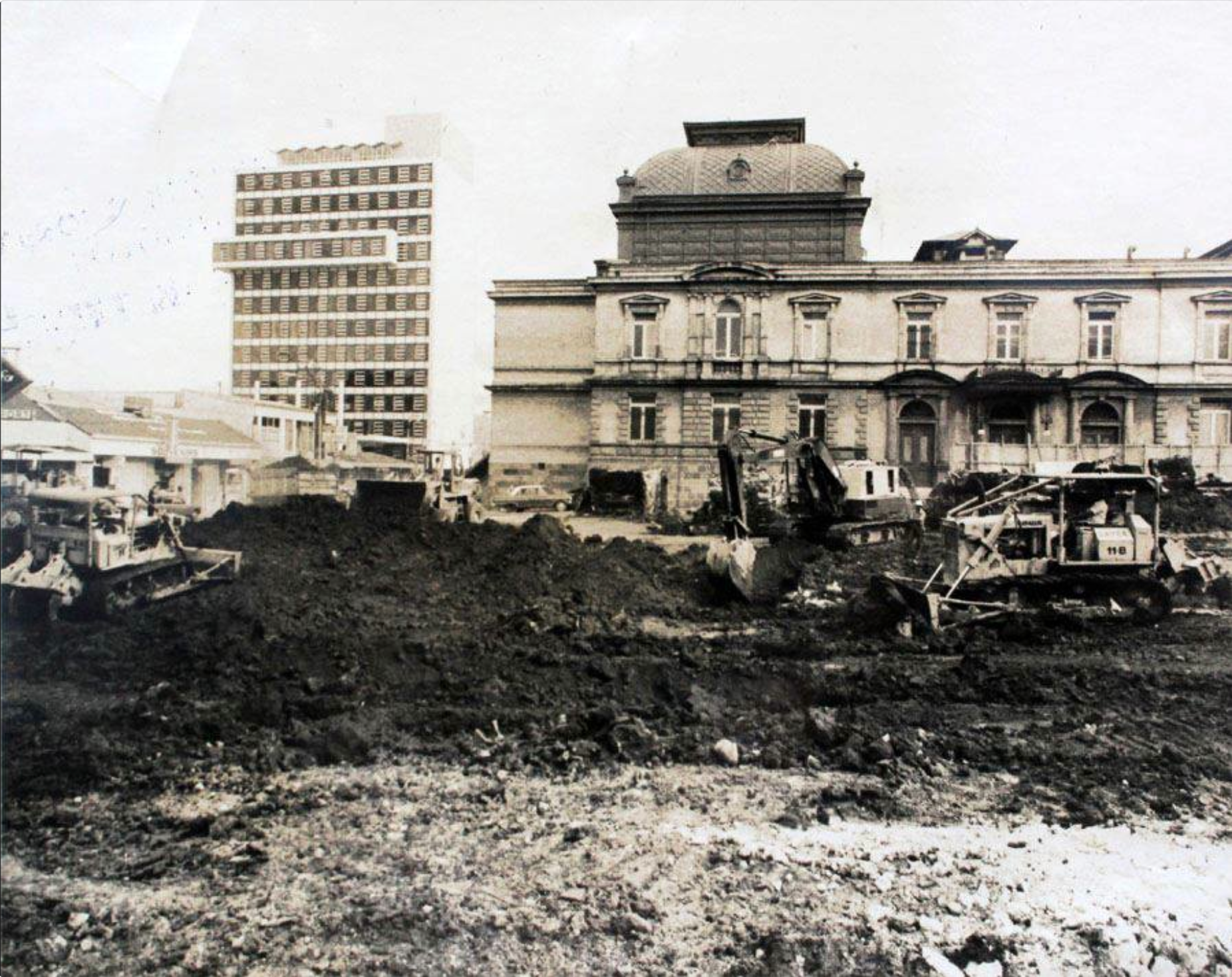 La imagen muestra maquinaria pesada operando frente a un edificio de valor arquitectónico e histórico, reflejando el proceso de modernización y desarrollo urbano de la capital costarricense.