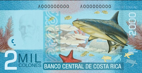 Reverso del billete de ₡2.000 de Costa Rica con la representación de un tiburón, peces y arrecifes coralinos, destacando la riqueza de los ecosistemas marinos del país.