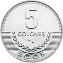 Reverso de una moneda plateada de 5 colones del Banco Central de Costa Rica. En la parte superior destaca el número "5", seguido de la palabra "COLONES". En la parte inferior aparece el acrónimo "B.C.C.R.", enmarcado por dos ramas de laurel que se extienden hacia los lados. El diseño presenta relieves sobre una superficie metálica de color plateado con borde circular decorado.
